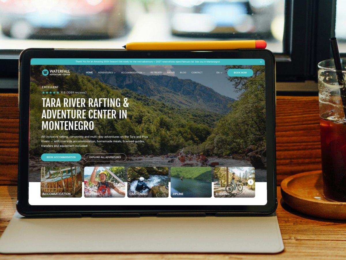 Waterfall Adventure Center homepage on a tablet on a café counter, next to an iced coffee